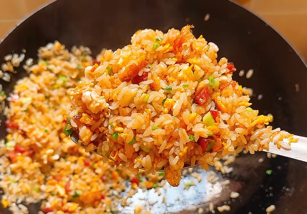 Home-style egg fried rice with diced vegetables lifted from a wok