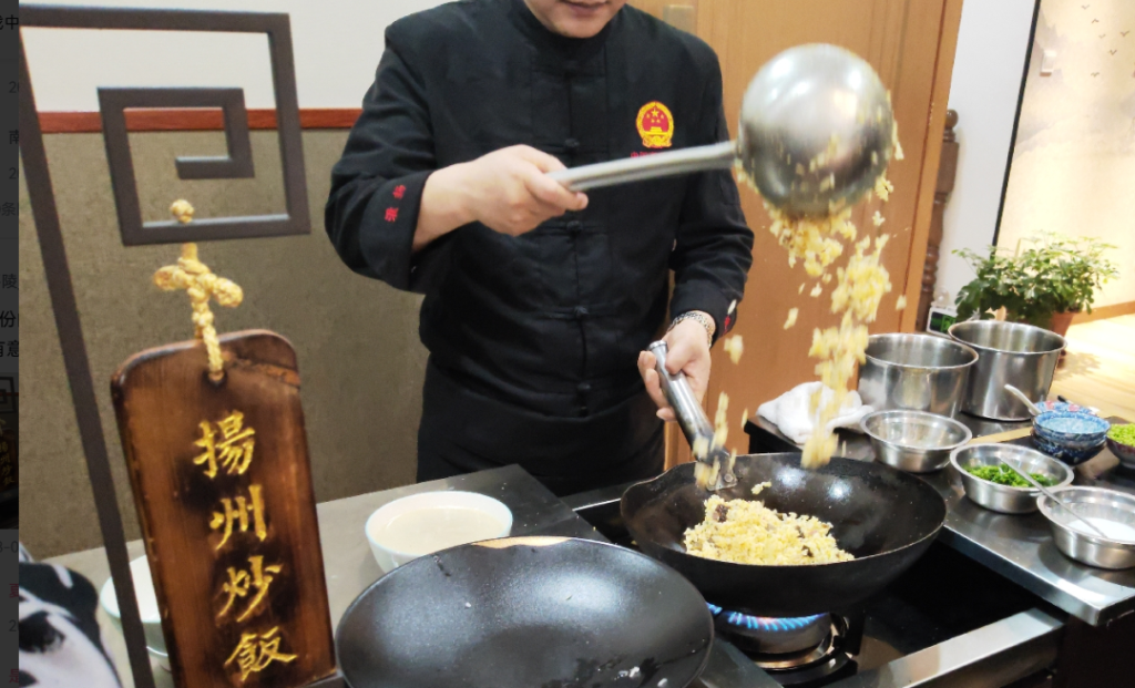 Chef tossing Yangzhou fried rice in a wok during a live cooking demonstration