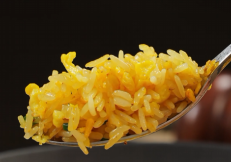 Spoonful of golden egg fried rice with separate rice grains