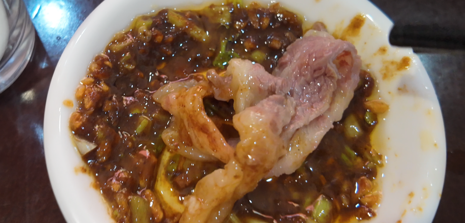 Cooked beef dipped in shacha sauce with chopped scallions
